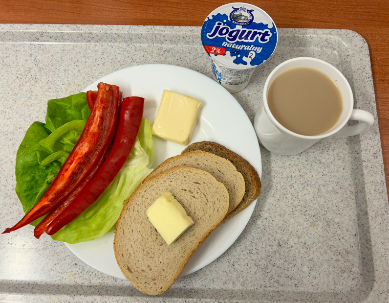 Na zdjęciu znajduje się: Jogurt naturalny, Kawa zbożowa z mlekiem, Chleb mieszany pszenno-żytni, Chleb Graham, Masło extra 82%, Ser topiony, Papryka świeża, ​​​​​​​Sałata zielona